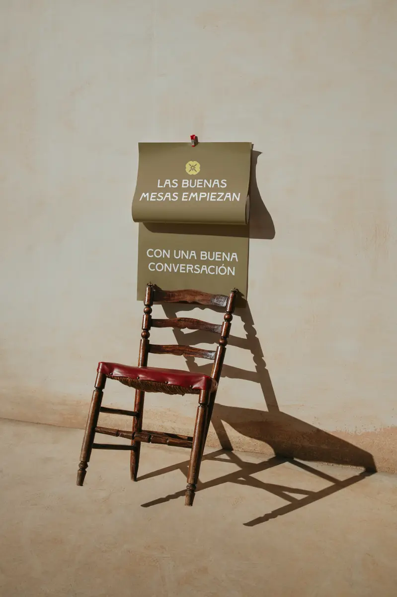 Silla de enea junto a un cartel de El Pintor: las buenas mesas empiezan con una buena conversación